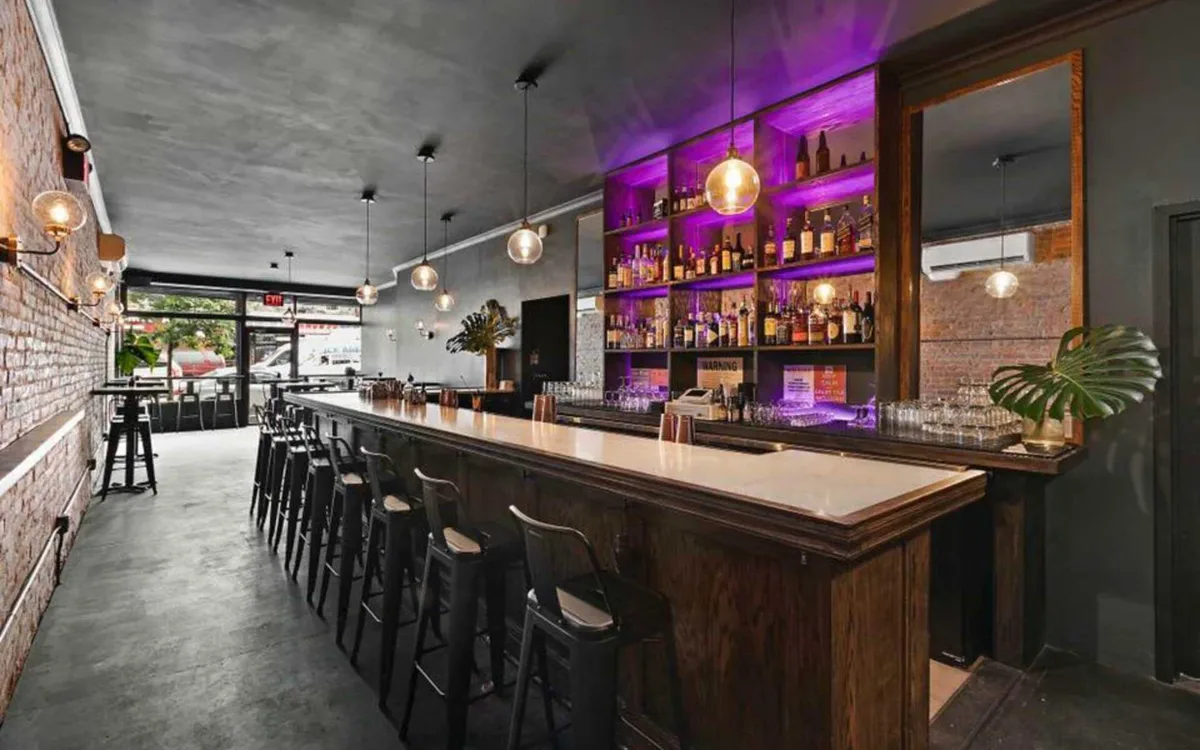 The long wood bar at L'Wren with purple back-bar lighting