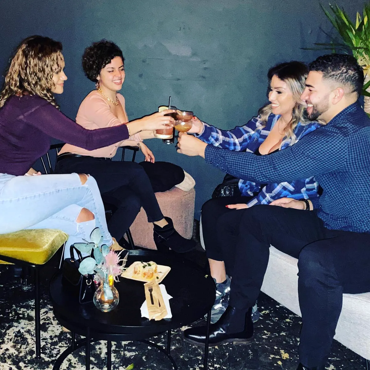 Friends toasting with cocktails on the couches at L'Wren