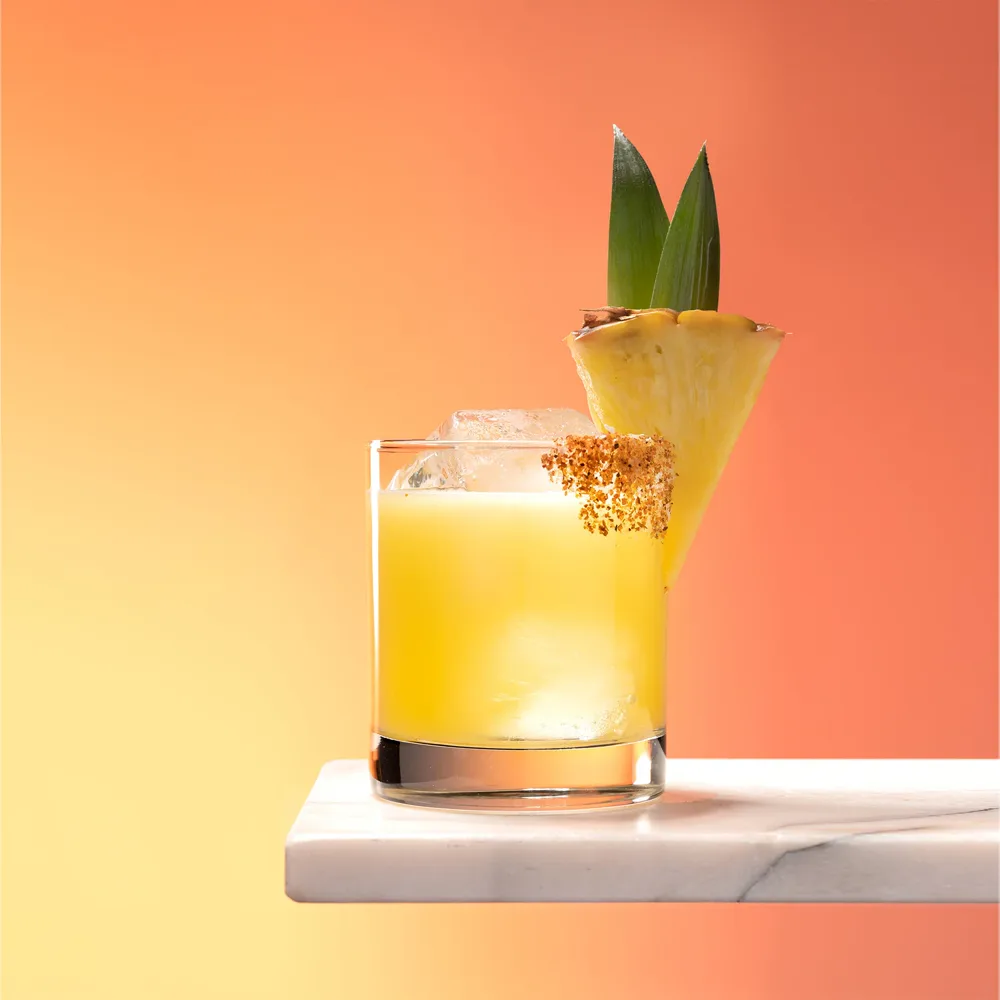 Up In Smoke cocktail with a pineapple wedge and tajin rim